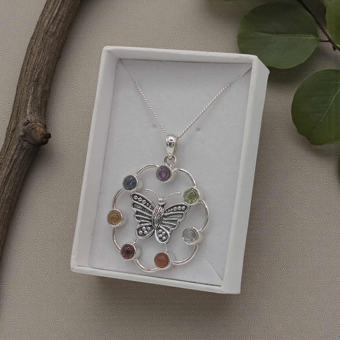 A sterling silver butterfly necklace with chakta gemstones on an 18 inch chain